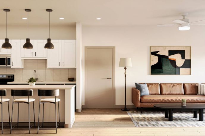 Allers Landing Modern open kitchen and living room with white cabinets, brown sofa, and bar stools at an island.