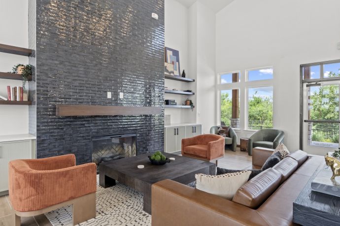 Allers Landing Modern living room with tall black tiled fireplace, large windows, and contemporary furniture in neutral tones.
