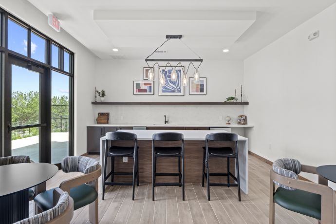 Allers Landing Modern kitchen area with bar seating, pendant lights, and large windows overlooking greenery.